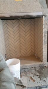 A fireplace interior showing a herringbone brick pattern during construction by Infinite Fire Features in Colorado Springs, CO.