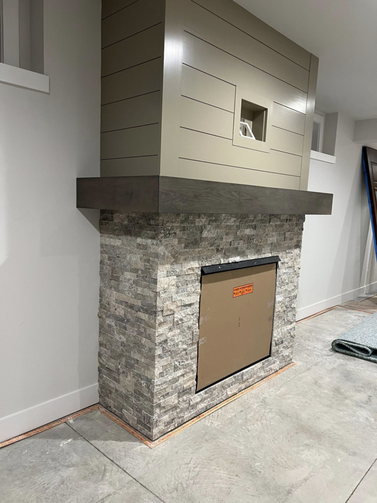 A newly installed fireplace with stone veneer and a modern shiplap surround by Tri Lake Construction in Madison, WI