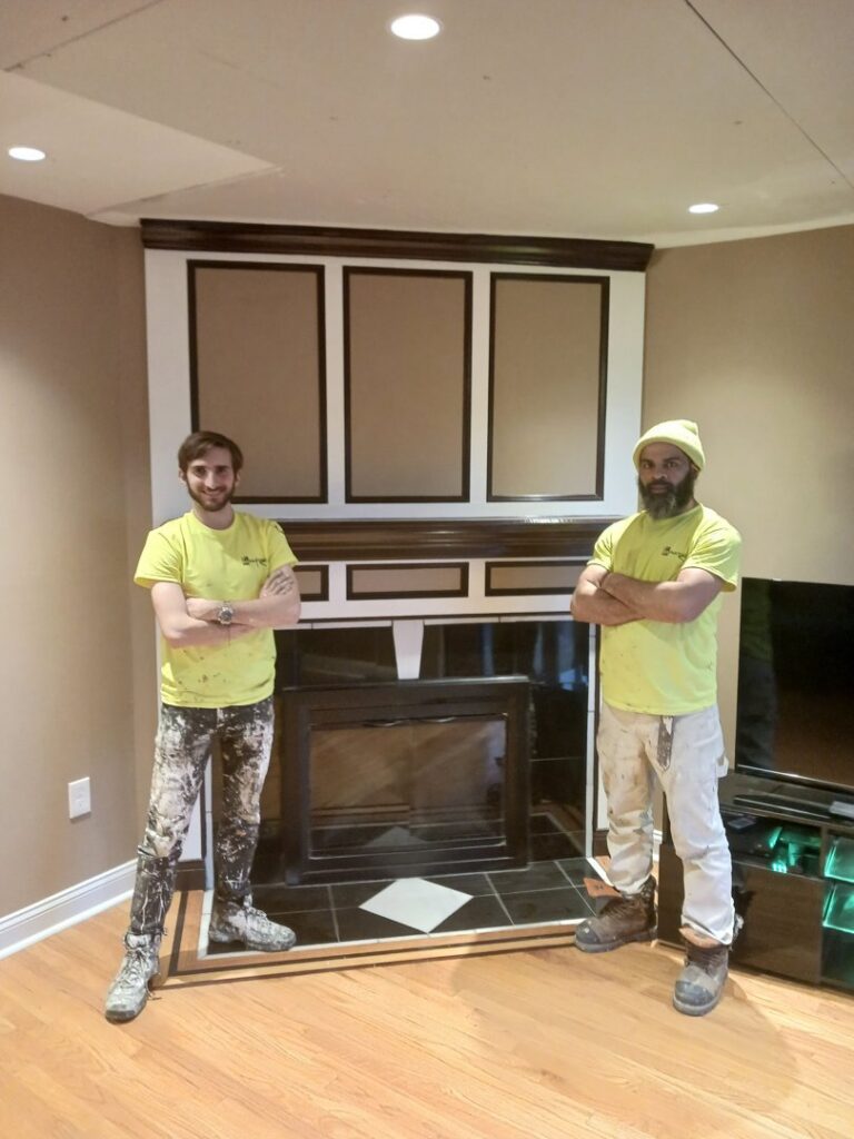 Two painters from GO Painting standing in front of a newly painted fireplace mantel in New Haven, CT