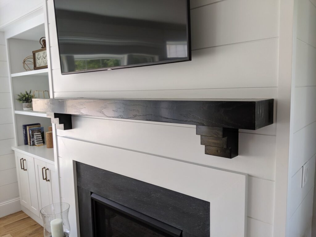 A newly installed fireplace mantel with a mounted television above it, completed by BizMick Construction in Coventry, RI.