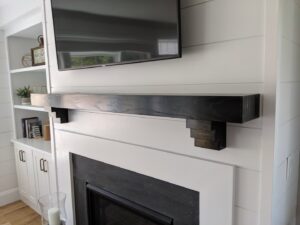 A newly installed fireplace mantel with a mounted television above it, completed by BizMick Construction in Coventry, RI.