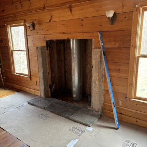Fireplace remodeling in progress, showing the flue pipe and protected flooring, by United Brothers Insulation and Remodeling in Athens, GA.