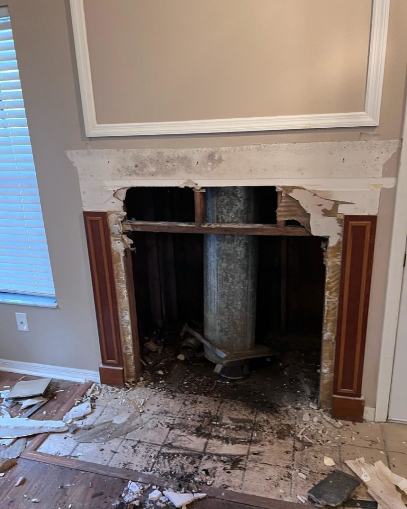 A fireplace mantel and surround demolished, exposing the flue pipe during a renovation project by PJC Solution Inc in Orlando, FL.