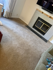 A living room with a fireplace renovation in progress, showing partially painted brick by Pineda's Construction LLC in Colorado Springs, CO