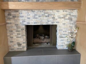 Close-up detail of a stone veneer fireplace and wooden mantel installed by Titan Handyman Services in Lewes, DE