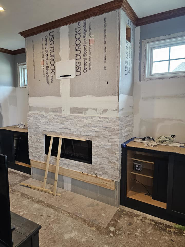 Handyman Dan INC installing stone veneer on a fireplace and built-in cabinets in Fremont, NE.