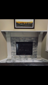 A newly installed fireplace with stone veneer and a white mantel by Juan The Handyman LLC in Kansas City, KS