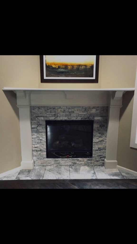 A newly installed fireplace with stone veneer and a white mantel by Juan The Handyman LLC in Kansas City, KS