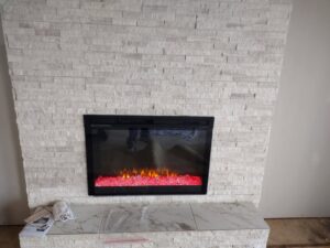 A newly installed fireplace with a stone veneer surround and electric insert by Westlake Ace Handyman Services Kansas City Metro in Lenexa, KS.