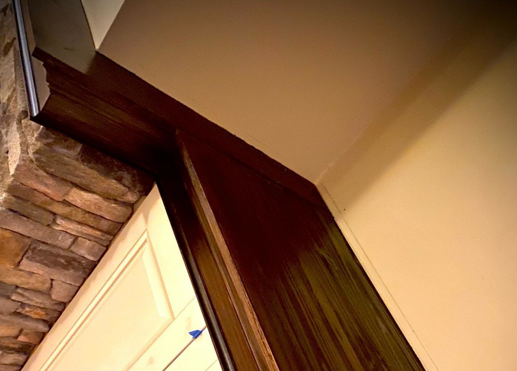 Detailed view of the stone and dark wood trim on a custom fireplace by Mohawk Home Improvement of Syracuse LLC in Syracuse, NY.