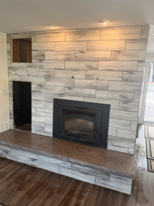A newly tiled fireplace surround with wood-look planks installed by Burrell Tile INC in Cottage Grove, OR.