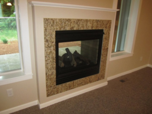 A newly installed fireplace with a decorative tile surround and white trim by Qual-i-Tee bilt homes - Steve Johnson in Salem, OR.