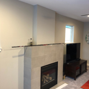 A fireplace tiling and custom mantel installation in progress by Smitty Construction Services LLC in Bend, OR.