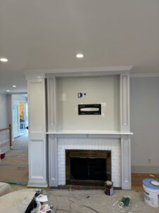 Fireplace area with a TV mount installed and painting supplies, showing work in progress by Garbatini Contracting in Wallingford, CT.
