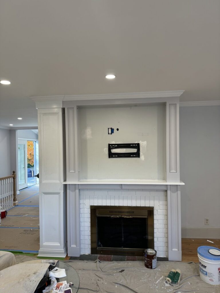 Fireplace area with a TV mount installed and painting supplies, showing work in progress by Garbatini Contracting in Wallingford, CT.