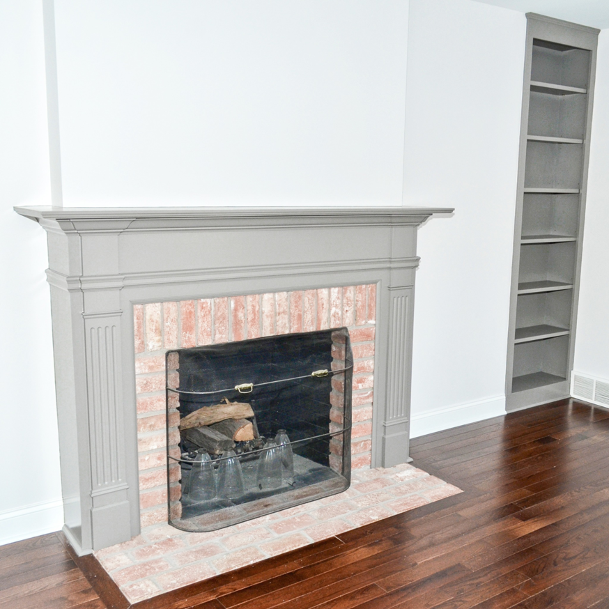 A renovated fireplace with a grey mantel and built-in bookshelf by Patriot Construction in Rochester, NY