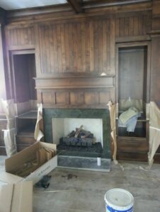A fireplace installation with a wooden mantel and surround, showing work in progress by Infinite Fire Features in Colorado Springs, CO.