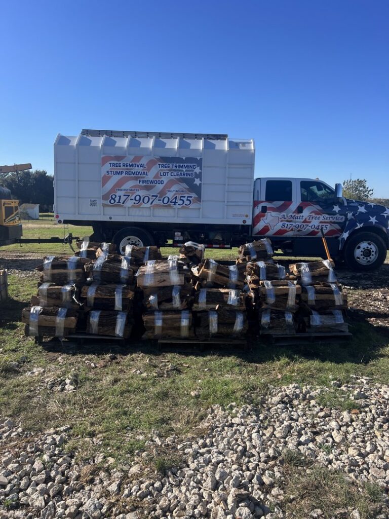 Bundles of firewood stacked next to a tree service truck from A. Matt Tree Service in Fort Worth, TX.