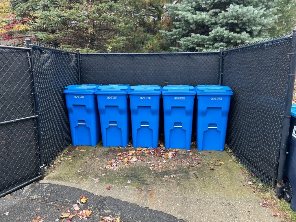 Five blue residential trash and recycling bins lined up by Champion Waste Services in Londonderry, NH.