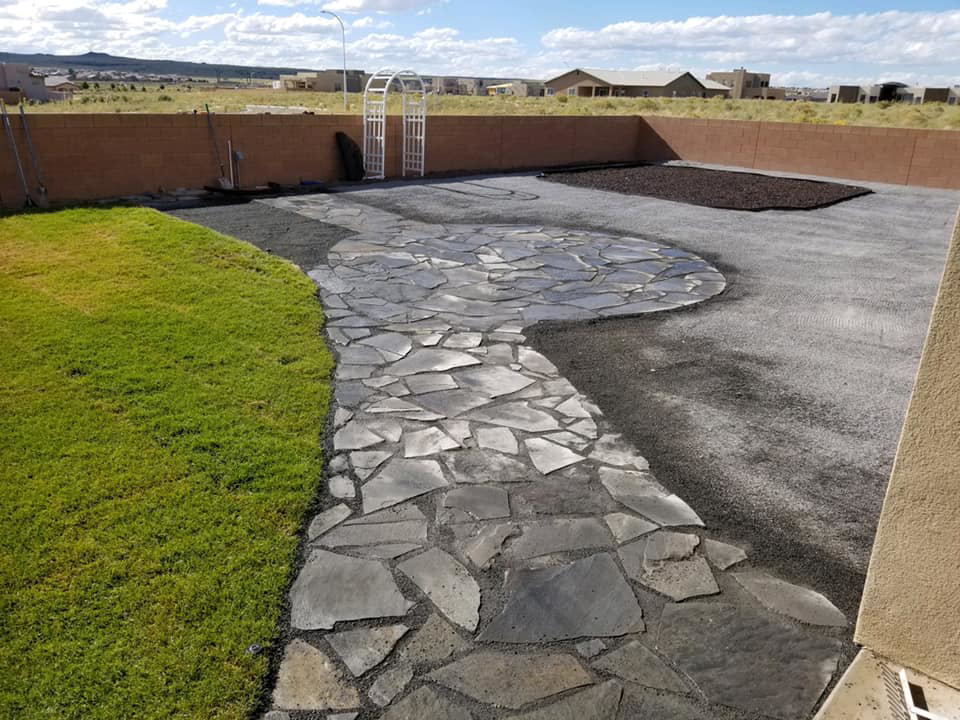 Newly installed flagstone patio and landscaping with fresh grass in a backyard by AV Handyman Services in Rio Rancho, NM.