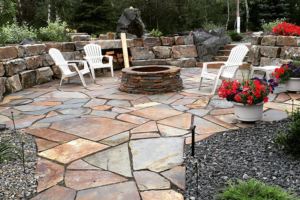 A beautifully designed flagstone patio with a stone fire pit and retaining wall by Contractors Stone Supply in Plano, TX