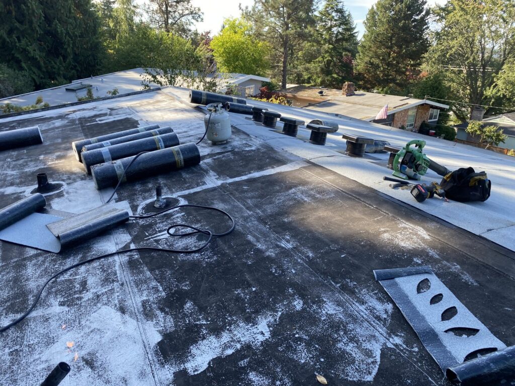 Flat roof installation with rolled roofing materials and tools by Sunny's roofing LLC in Denver, CO.