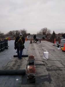 Workers applying new flat roofing material during a commercial roof installation by Pro DK Contractor LLC in Chicago, IL.