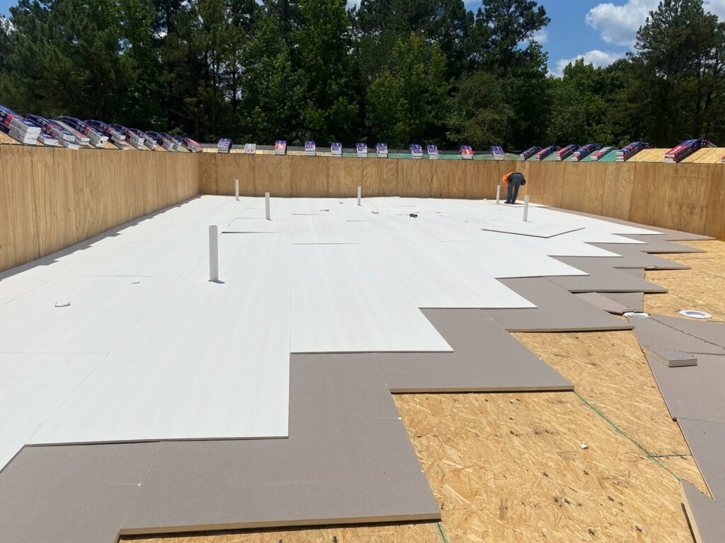 Insulation boards being installed on a commercial flat roof, a service offered by Roofing Experts Care in Charlotte, NC.