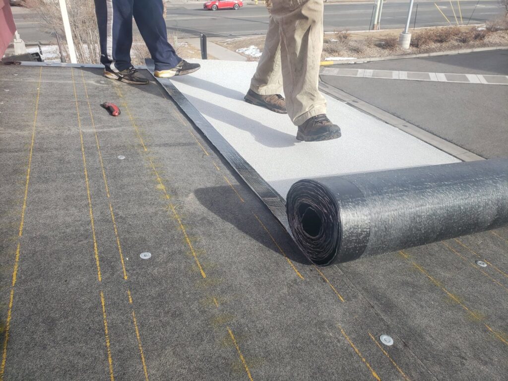 Workers installing a new membrane on a flat roof, a specialized service from Jesse Roofs Co. in Denver, CO
