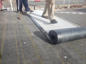 Workers installing a new membrane on a flat roof, a specialized service from Jesse Roofs Co. in Denver, CO