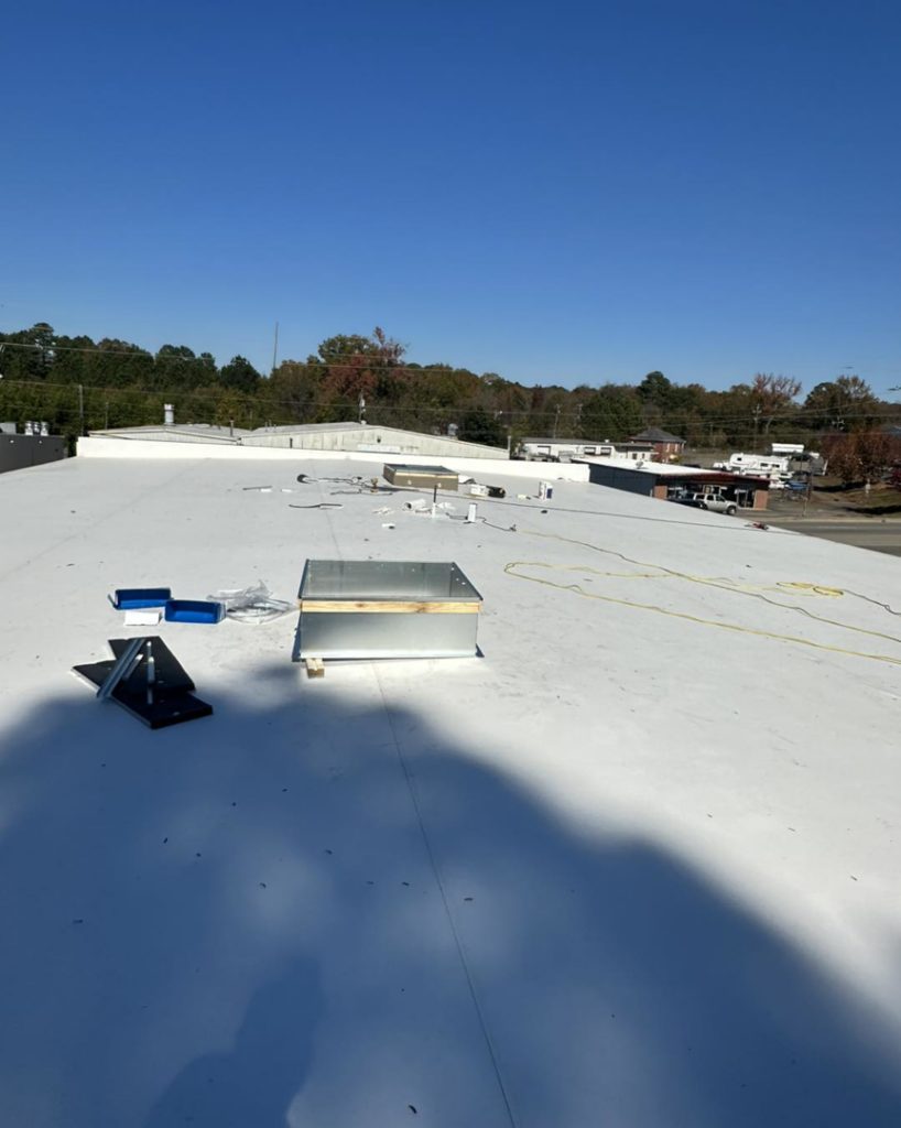 A new skylight or roof hatch being installed on a flat commercial roof by Carolina DR & Roofing in Raleigh, NC.