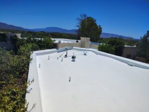 A large flat roof with a fresh white coating applied by Mayitos roofing LLC in Tucson, AZ.