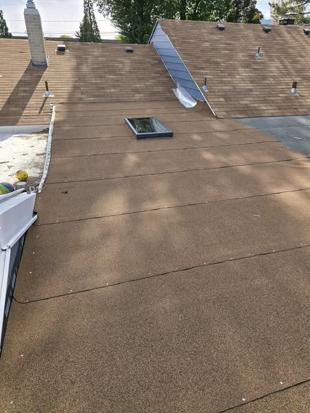 A flat roof with a skylight, covered in new brown granular roofing material, demonstrating roofing services by Tillman's Handyman Service in Sparks, NV.