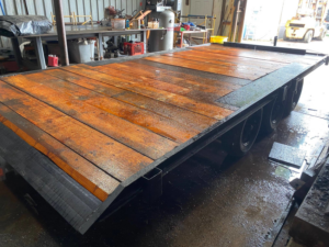 A flatbed trailer with a newly repaired or fabricated wooden deck in the workshop by Get it-Got It-Gone, LLC. in Goodview, VA.