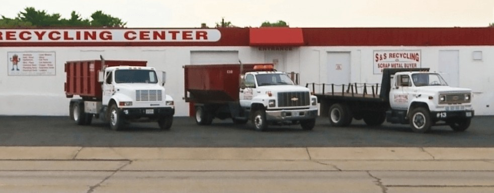 A fleet of SS ROLL OFF Dumpsters trucks and dumpsters parked at their recycling center in Rockford, IL.