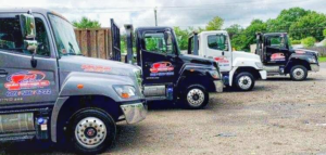A fleet of flatbed tow trucks ready for junk car removal at First Class Auto Salvage Inc. in Trenton, NJ