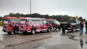A fleet of Valiant Electric Inc. service vans and a pickup truck parked on a wet lot in Kenosha, WI.