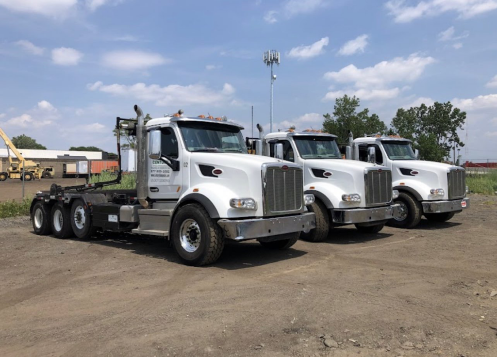 A fleet of white roll-off trucks from Century Waste Management, ready for junk removal services in Sterling Heights, MI.