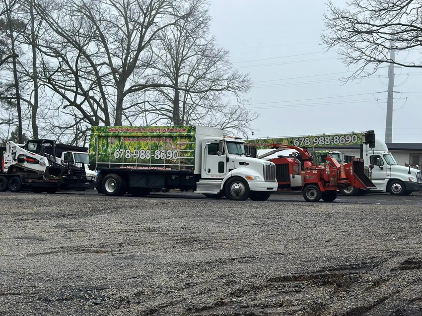 A fleet of tree service equipment, including trucks, a wood chipper, and a bobcat, from Danilo's Tree Service and Landscaping in Dallas, GA.