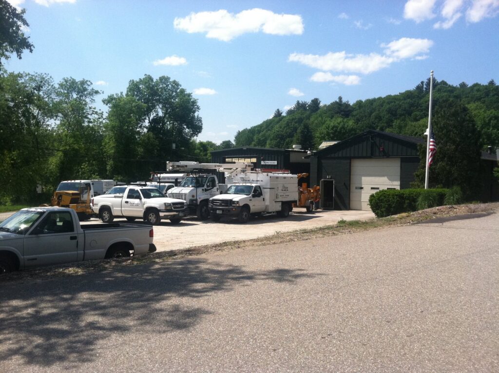 A fleet of Collins Tree Service, Inc. trucks and equipment parked outside their business location in Hooksett, NH.