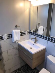 A modern bathroom featuring a floating vanity, mirror, and decorative tile border installed by Pro Remodel LLC in St. Charles, MO.
