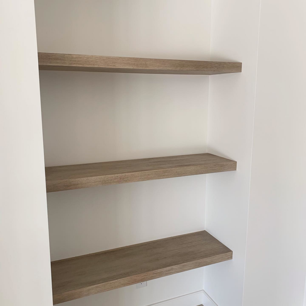 Floating wooden shelves installed in a white alcove by Mountain Door and Trim in Phoenix, AZ.