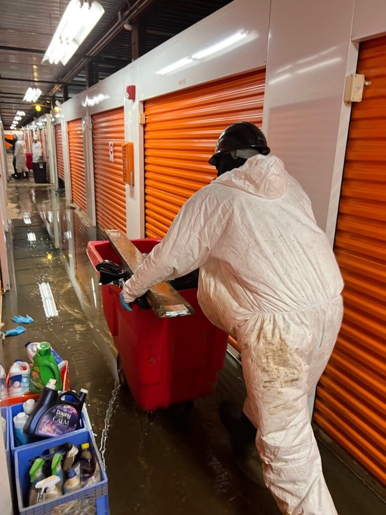 A worker in a protective suit performing flood cleanup in a storage unit for Professional Restoration in Jersey City, NJ