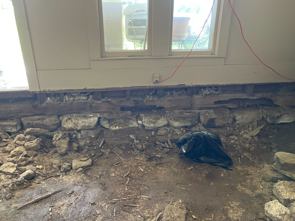 A room with the floor removed, exposing the stone foundation and dirt, showing demolition work by HW Handyman Services in Springfield, MO.
