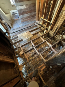 A floor undergoing demolition, exposing joists and plumbing during a renovation by KMAC Construction in Youngsville, LA.