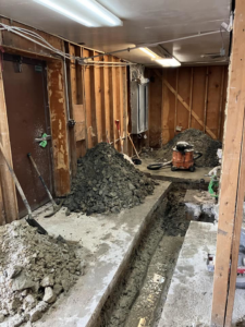 Floor demolition work with trenches, dirt piles, and a shop vacuum at a JB Renovations project in Houston, TX.