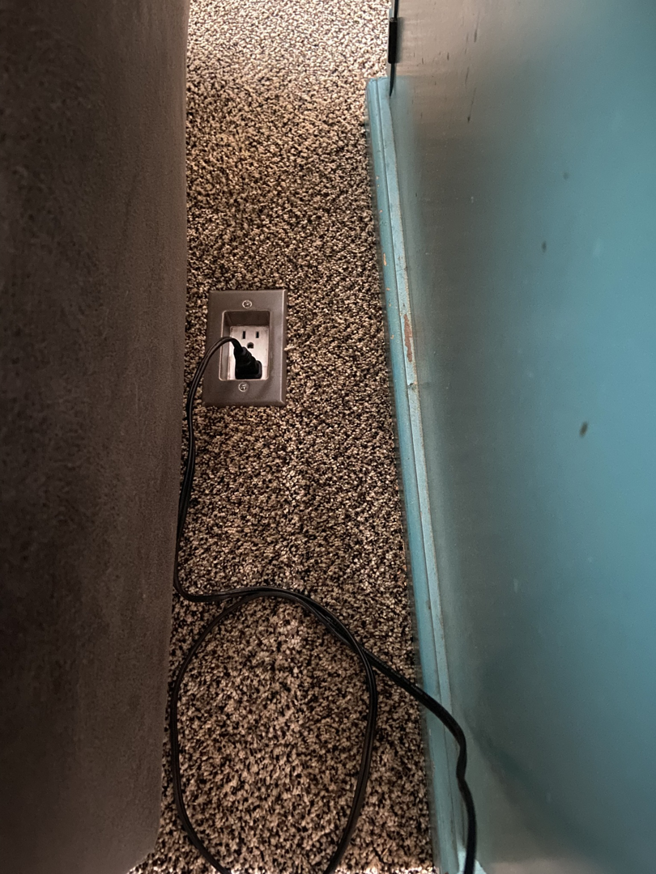 A newly installed floor electrical outlet with a cord plugged in, completed by Green River Utilities in Caldwell, ID.
