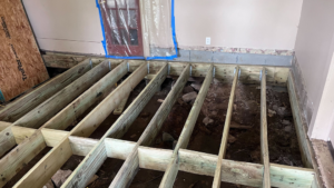 New floor joists being installed over an excavated area, indicating structural repair work by HW Handyman Services in Springfield, MO.