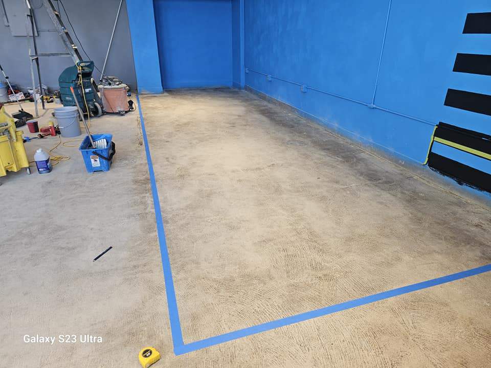 Concrete floor prepared with blue tape for painting or coating by Logical Drywall and Painting in St. Louis, MO.