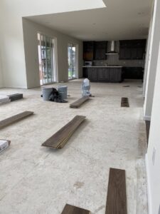 Floor repair or installation in progress, showing exposed joists, pipes, and new floorboards by IHS flooring LLC in Brighton, CO.